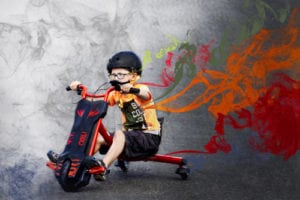 8 year old boy riding red drift trike with multi-coloured smoke trails